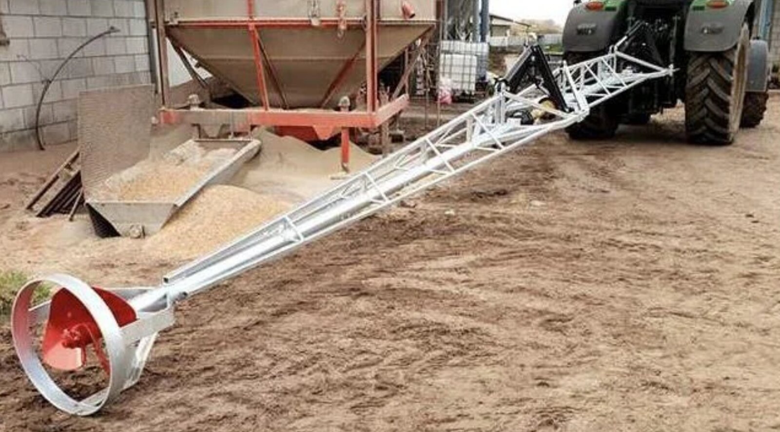 Traktordriven gödselomrörare ansluten till traktor i gårdsmiljö.